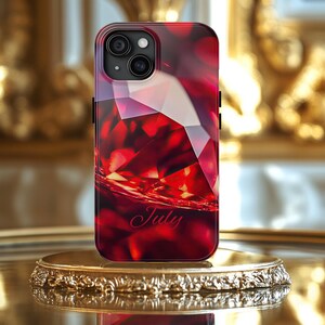 May include: A red phone case with a geometric design and the word "July" printed on it.