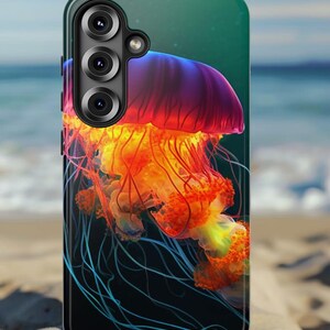 May include: A phone case featuring a vibrant jellyfish design. The case showcases a colorful jellyfish with a purple, orange, and yellow color scheme against a dark background. The phone case is black and has three camera lenses.