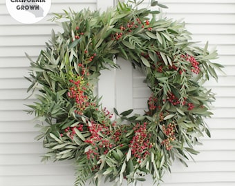May include: A green olive branch wreath with red berries. The wreath is decorated with the text "100% CALIFORNIA GROWN".