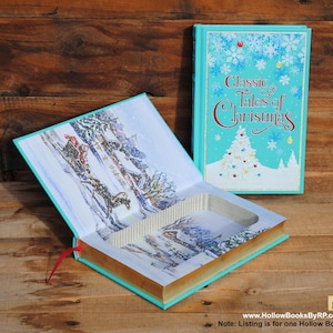 May include: A teal blue hollow book with a winter scene on the cover. The book is open to reveal a hidden compartment inside. The cover reads "Classic Tales of Christmas".