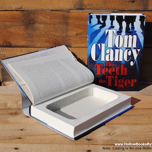 Op de afbeelding: Een holle boekenkluis vermomd als een exemplaar van "De Tanden van de Tijger" van Tom Clancy. Het boek is open om een verborgen compartiment aan de binnenkant te onthullen.