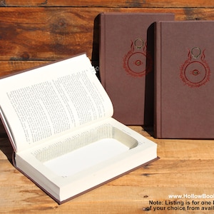 May include: A brown hollow book with a rectangular compartment, shown open. Two more books with brown covers and a red circular design are visible. The books are on a wooden surface. The website address www.HollowBooksByRP.com is visible.