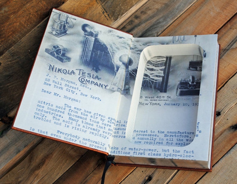 May include: A vintage book with a hidden compartment that reveals a photograph of Nikola Tesla's laboratory. The book's cover features the text "Nikola Tesla Company" and a letter addressed to J.P. Morgan. The letter discusses the importance of nitric acid in wartime industries.