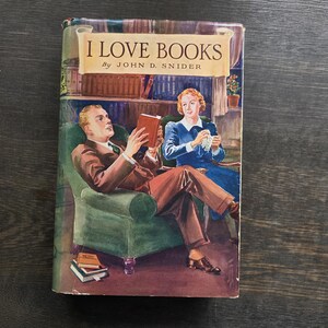 May include: Vintage book cover titled "I Love Books" by John D. Snider. The cover art depicts a man in a brown suit reading a book in a green armchair, and a woman in a blue dress. The background shows a library setting.