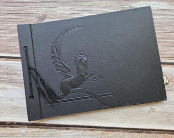 Art deco-style Pegasus scrapbook. Black debossed cover. Black pages.  12" x 8-1/2"
