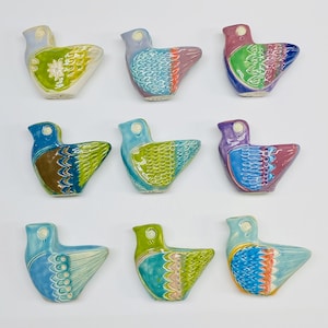 May include: Nine ceramic bird figurines with different coloured glazes and patterns. The birds are all facing the right side of the image. The birds are all in a row, with three birds in each row.