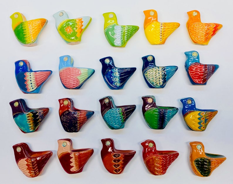 May include: Twenty-four colourful ceramic bird figurines with various patterns and designs. The birds are all facing the right side of the image and are arranged in four rows of six birds each.