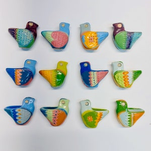 May include: Twelve ceramic bird figurines in a variety of colours and patterns. Each bird has a small hole on the top, suggesting they may be ornaments or decorative items.