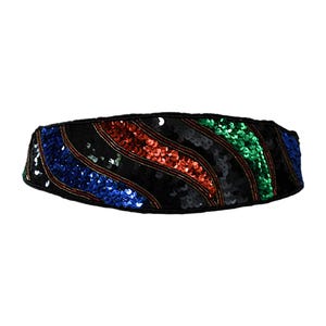 May include: A black sequined belt with diagonal stripes in blue, red, and green. The belt has a wide design and is likely for fashion or costume use. The sequins are sewn onto a black fabric base.