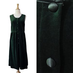 May include: A sleeveless dark green velvet dress featuring a round neckline and a full-length front button placket. The garment has a gathered waistline and matching fabric-covered buttons that extend from the neckline down to the hemline.