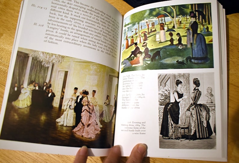 以下が含まれることがあります： 歴史的なファッションのイラストが掲載された開いた本。ある画像は、フォーマルな服装の人々がいる舞踏会のシーンを描いています。別の画像は、人物と犬がいる公園のシーンを示しています。3番目の画像は、ドレスを着た2人の女性を示しています。