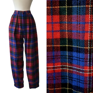 May include: High-waisted trousers featuring a vibrant red, blue, green, and yellow plaid tartan pattern. The pants have a structured waistband with a button closure, front pleats, and a straight-leg cut, shown in full and in a detailed fabric view.