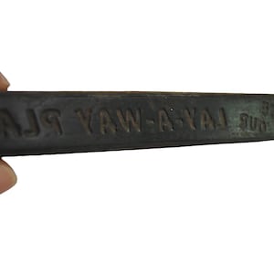 May include: A dark gray rectangular stamp with the text "LAY-A-WAY PLAN" and "SUB 121" in embossed lettering. The stamp is held by a hand against a white background.