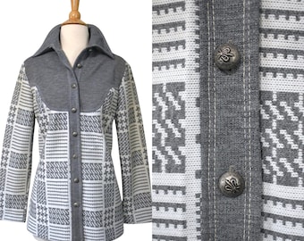 May include: A long-sleeve button-up shirt featuring a gray solid-colored yoke and collar, contrasted with a white and gray geometric houndstooth pattern on the body and sleeves. The shirt includes silver-toned metal buttons with a fleur-de-lis design.