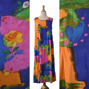 May include: A sleeveless maxi dress featuring a vibrant, abstract floral print in shades of orange, blue, pink, and green. The garment has a round neckline and a loose, flowing silhouette, showcasing a large yellow rose motif on the left side.