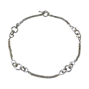 May include: Silver-toned necklace featuring a mix of chain styles. The necklace has a toggle clasp closure and includes sections of delicate, tightly linked chains and larger, open link designs. The overall design is symmetrical and modern.