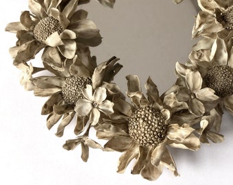 May include: A round mirror with a white, floral frame. The frame is made of sculpted flowers with a textured, aged look.
