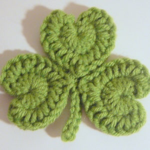 May include: A green crocheted shamrock with three leaves and a stem.