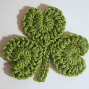 May include: A green crocheted shamrock with four leaves.