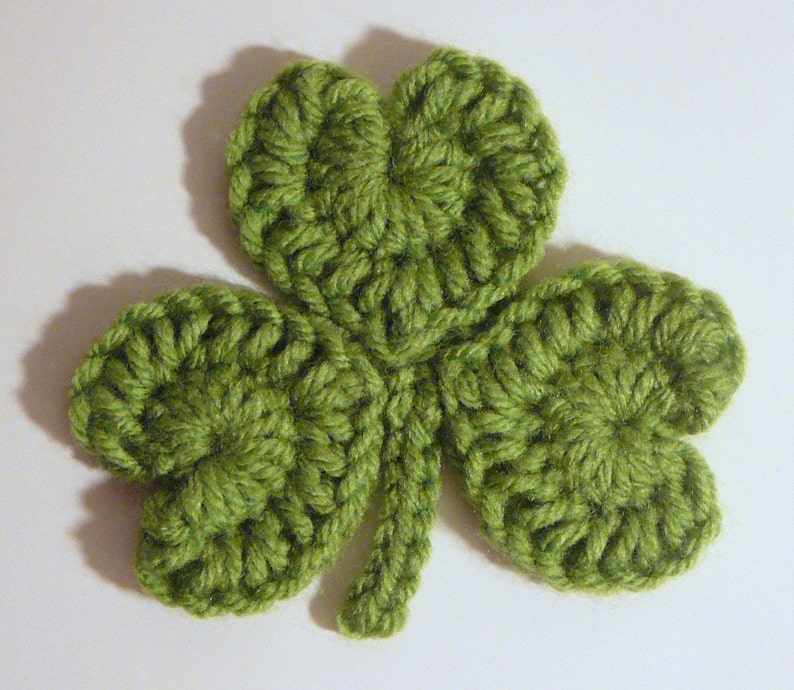 May include: A green crocheted shamrock with four leaves.