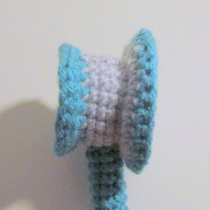 Peut inclure: Un jouet en crochet avec une t&ecirc;te ray&eacute;e bleu et blanc et un corps bleu.