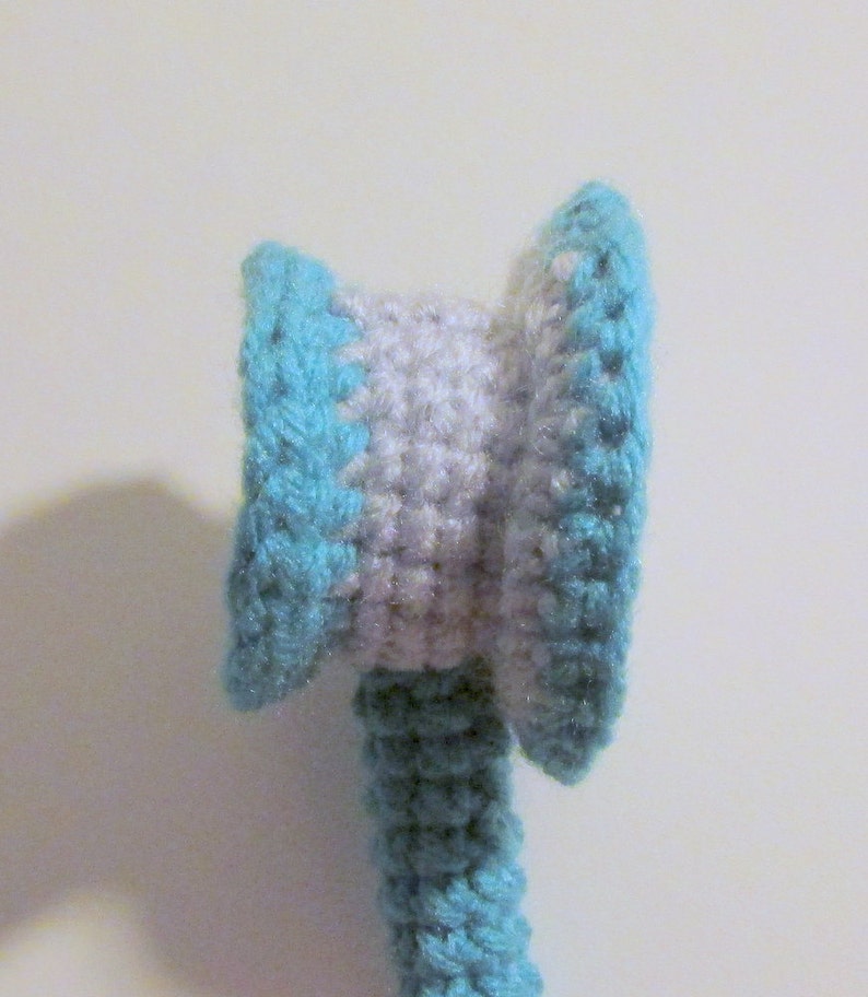Peut inclure: Un jouet en crochet avec une t&ecirc;te ray&eacute;e bleu et blanc et un corps bleu.