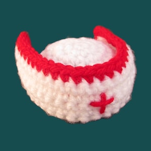 May include: White crocheted nurse's hat with a red brim and a red cross.