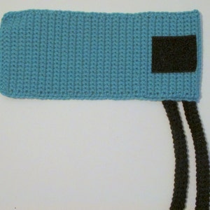 Peut inclure: Un bandeau en crochet bleu clair avec un patch en feutre noir et deux liens en crochet noir.