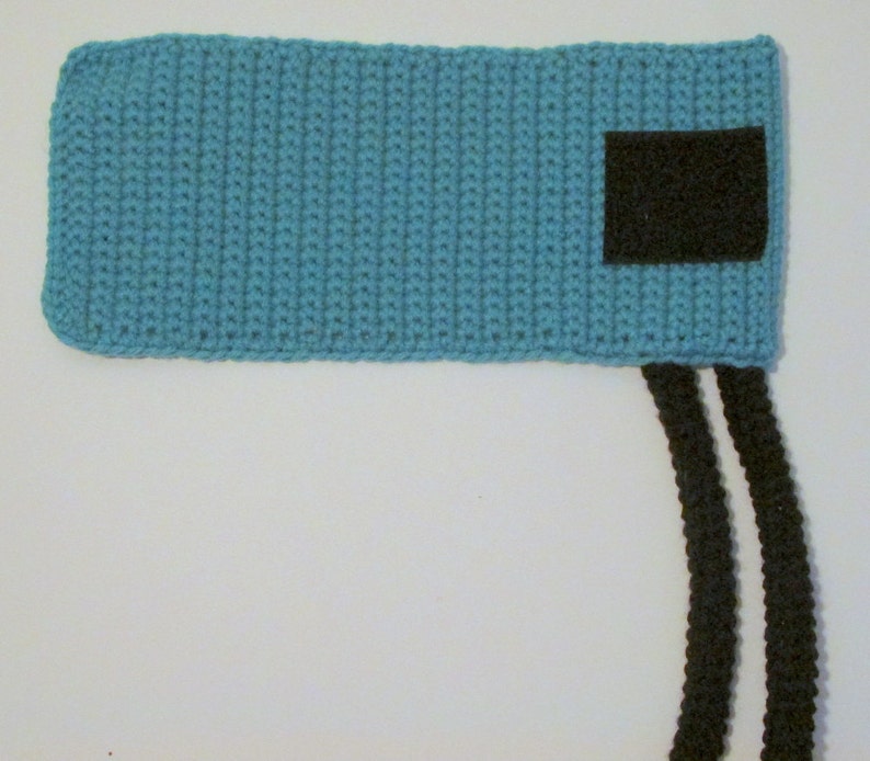 Peut inclure: Un bandeau en crochet bleu clair avec un patch en feutre noir et deux liens en crochet noir.