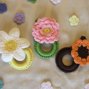 May include: A set of crocheted flower-shaped rings in various colors, including pink, white, yellow, orange, and brown. The rings are made with a soft, textured yarn and are perfect for adding a touch of whimsy to any home decor.