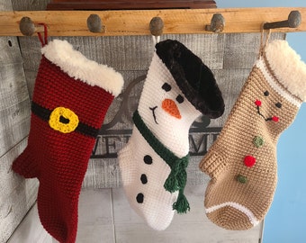 May include: Three crocheted Christmas stockings hanging on a wooden rack. The stockings are decorated with a snowman, a gingerbread man, and Santa Claus.