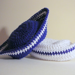 May include: Two crocheted hats in a sailor style. One hat is white with a blue trim and the other is blue with a white trim.