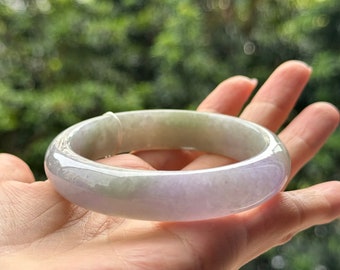 May include: A light green and lavender jade bangle bracelet. The bracelet is smooth and polished.