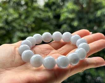 May include: A bracelet made of light blue jade beads. The beads are round and smooth, and the bracelet is strung on a clear elastic cord.
