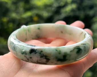 Op de afbeelding: Een jade armband met een wit en groen marmerpatroon. De armband is glad en gepolijst.