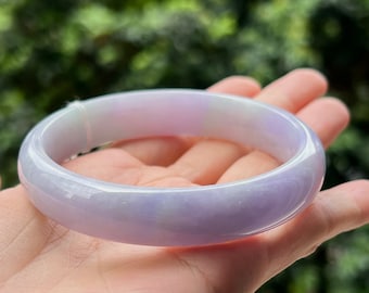 May include: A lavender jade bangle bracelet with a smooth, polished finish. The bracelet is a light purple color with a hint of green.
