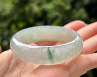 May include: A light green jade bangle bracelet with a smooth, polished finish.