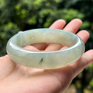 Può includere: Un braccialetto in giada verde chiaro con una finitura liscia e lucida. Il braccialetto è spesso e ha una leggera curva.