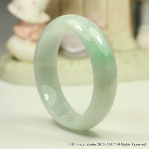 Può includere: Un braccialetto di giada verde chiaro. Il braccialetto è liscio e lucido, con un aspetto leggermente traslucido.