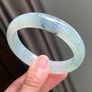 Può includere: Un braccialetto di giada verde chiaro con un motivo a spirale bianco e blu chiaro.