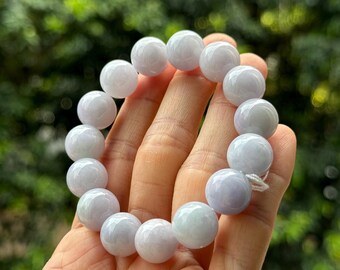 May include: A lavender jadeite bracelet with round beads. The bracelet is made of natural jadeite and is a beautiful example of this gemstone.