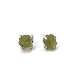 Puede incluir: Un par de pendientes de plata con pequeñas piedras preciosas verdes sin pulir.