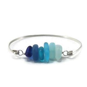 Könnte beinhalten: Ein silbernes Armreif-Armband mit einer abgestuften Reihe von blauen und türkisfarbenen Meerglassperlen.
