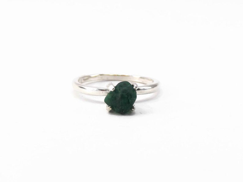 Puede incluir: Un anillo de plata con una piedra preciosa verde oscuro engastada en garras.