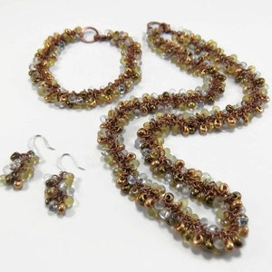 May include: A set of jewelry featuring a necklace, bracelet, and earrings. The pieces are made with copper wire and small, clear, and green glass beads.