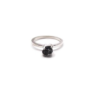 May include: A silver ring with a black, rough-cut gemstone.