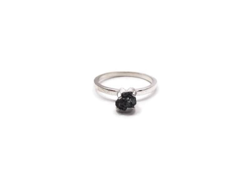 May include: A silver ring with a black, rough-cut gemstone.