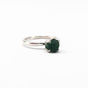Puede incluir: Un anillo de plata con una piedra preciosa verde oscuro engastada en garras.