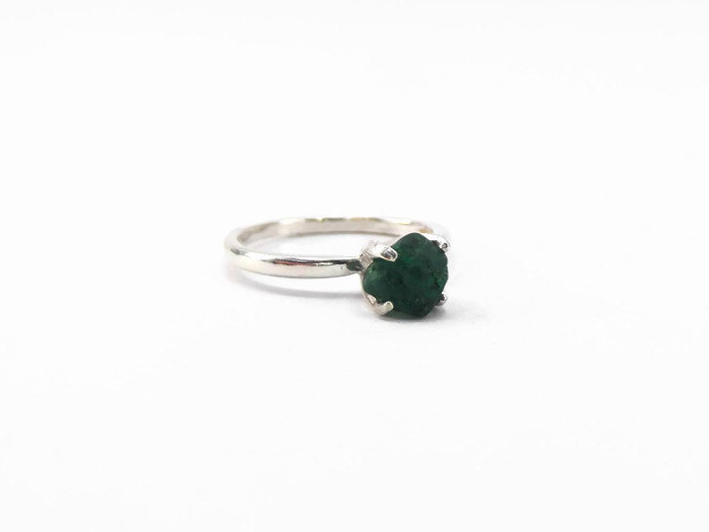Puede incluir: Un anillo de plata con una piedra preciosa verde oscuro engastada en garras.