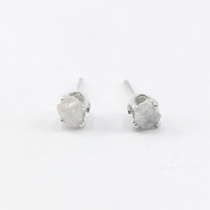 May include: A pair of silver stud earrings with rough, white diamond stones.